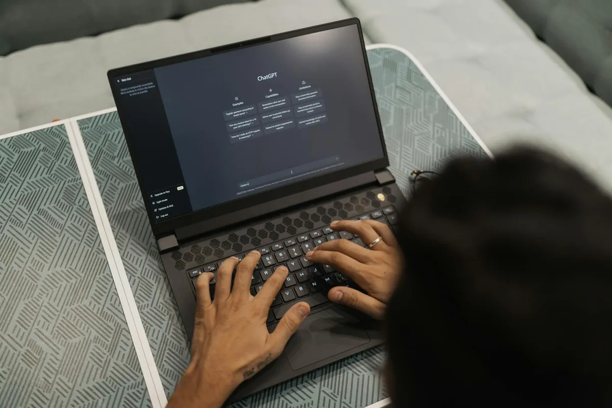 Mãos digitando num notebook com a tela de um assistente de inteligência artificial aberta