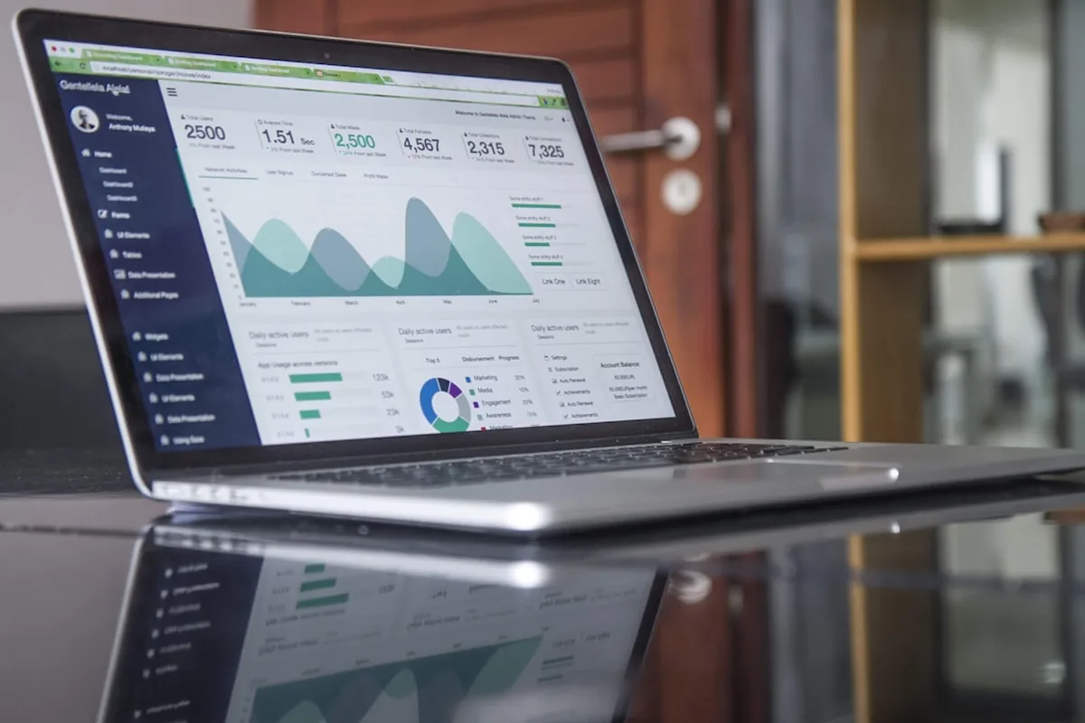 Notebook sobre mesa de vidro exibindo um painel com indicadores e gráficos